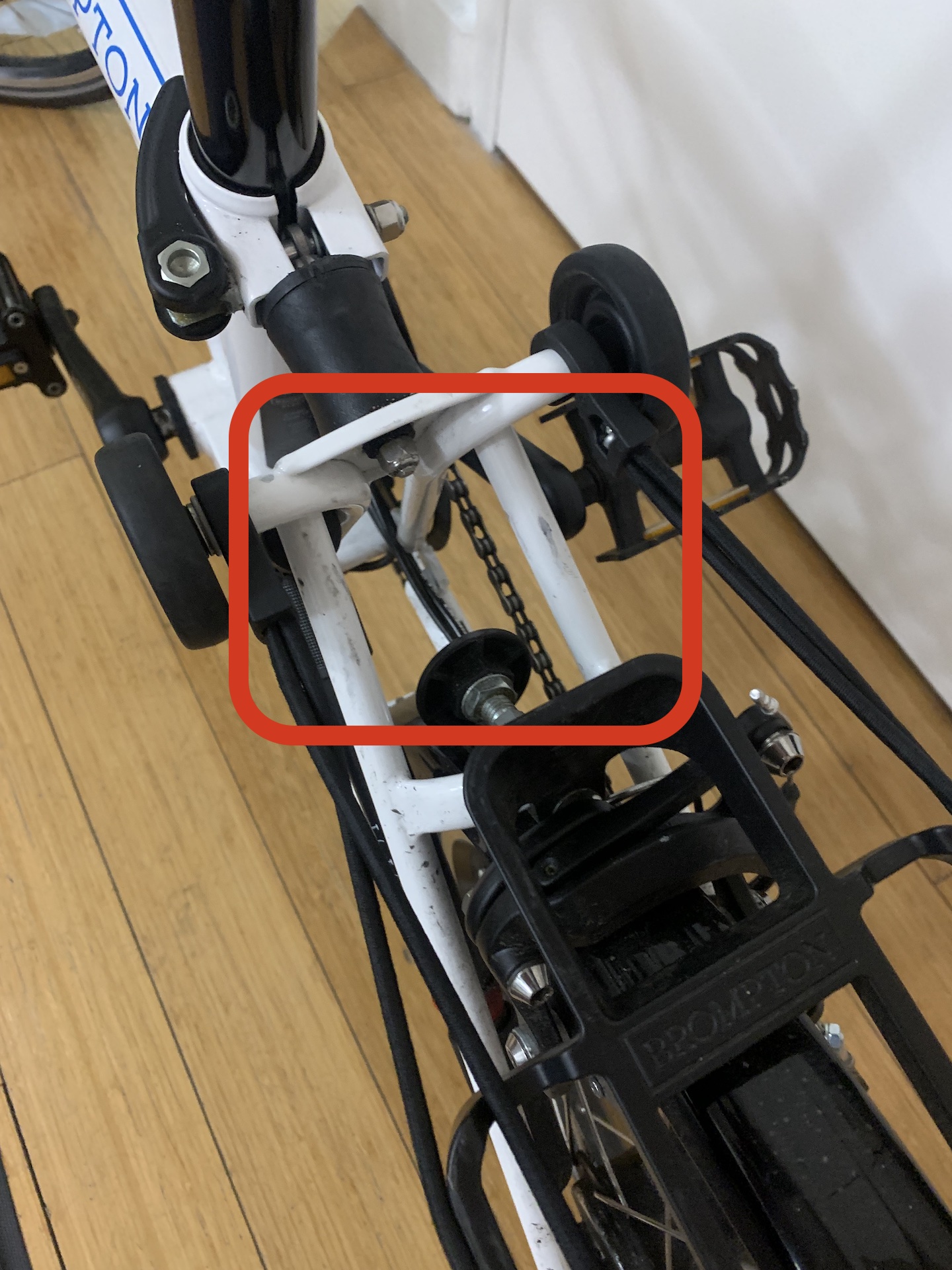 A close-up of the area of a Brompton folding bike, highlighting a gap between the shock absorber and the fender that a beach umbrella fits into